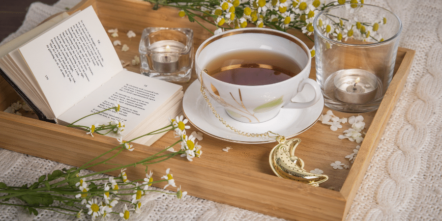Chamomile herbal tea in a glass mug with dried chamomile blossoms on a wooden table